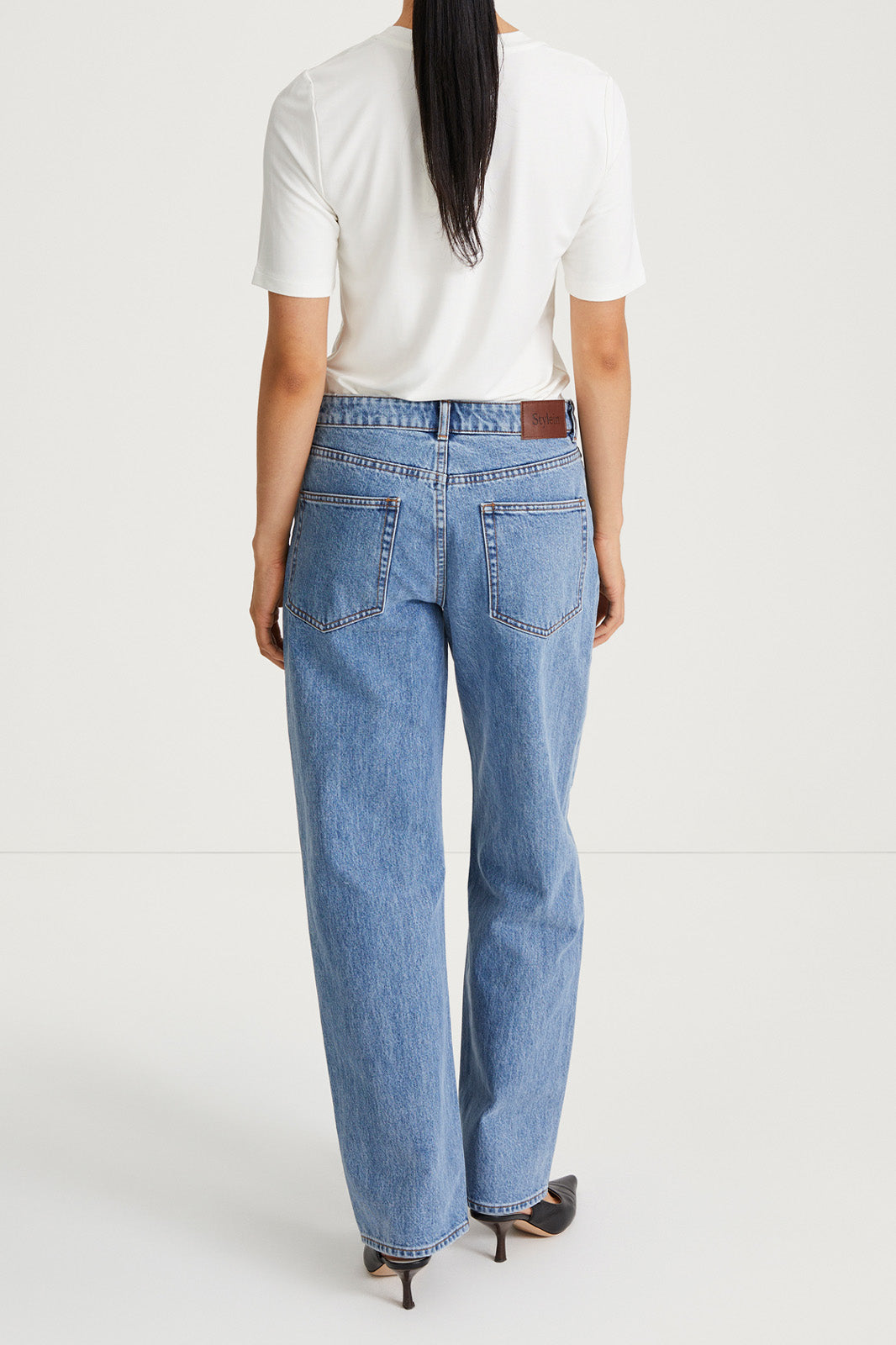 Person wearing blue jeans and a white shirt on a white background