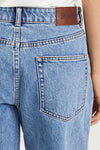 Close-up of blue jeans with a leather stylein label on a white background